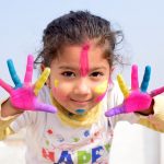 Girl showing both her hands painted with different colours.